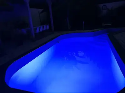 a swimming pool lit up in blue at night at Garden- pool apartman in Petrovice Donje
