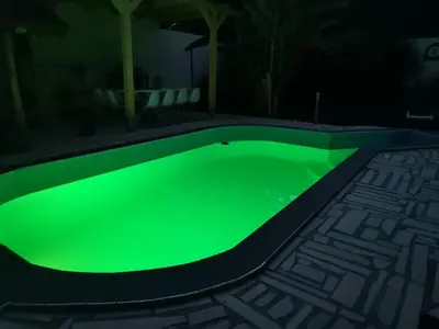 a green glow in the dark swimming pool at night at Garden- pool apartman in Petrovice Donje
