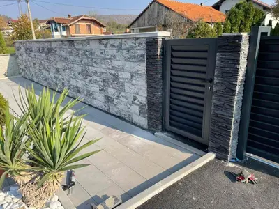 a fence with a gate and a stone wall at Una Bihac 4 in Bihać