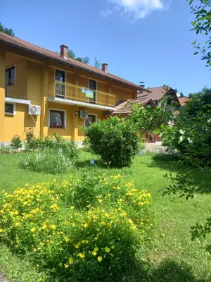 a yellow house with yellow flowers in the yard at Soba Dujaković in Banja Vrućica