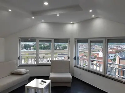 a living room with windows and a couch and a table at apartman Dani in Derventa