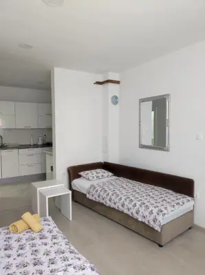 a bedroom with two beds and a white wall at Apartman Markešić 3 in Ripci