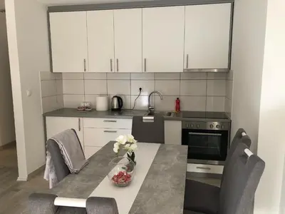 a kitchen with white cabinets and a table with flowers on it at Apartment Doris in Tomislavgrad