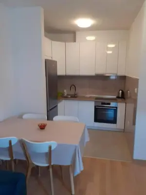 a kitchen with a table and chairs and a kitchen with white cabinets at Apartman Paradiso in Banja Luka