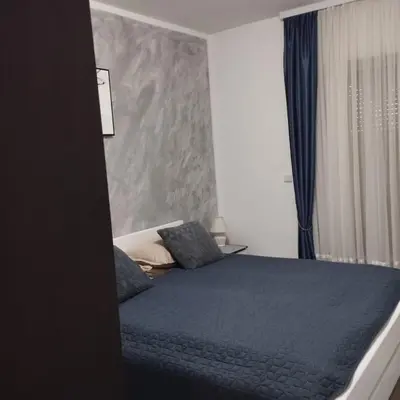 a bedroom with a bed with blue sheets and a window at Little Paradise in Bihać