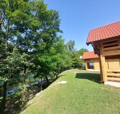 a yard next to a cabin with a river at Apartmani Kajkut in Banja Luka