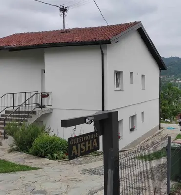 a white building with a sign in front of it at Ajsha Guesthouse in Jajce