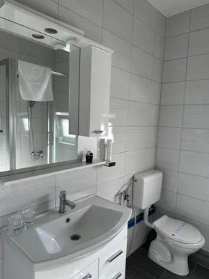a bathroom with a sink and a toilet and a mirror at Hotel Pilot in Cazin