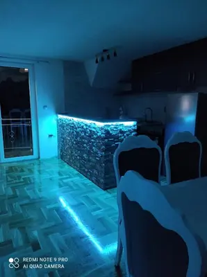 a room with chairs and a stone wall with blue lights at Apartman-vikendica Mihajlović in Banja Luka
