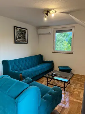 a living room with a blue couch and a table at Apartman-vikendica Mihajlović in Banja Luka