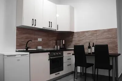 a kitchen with white cabinets and a table with black chairs at Stan na dan Sebastijan in Banja Luka