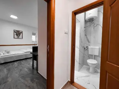 a bathroom with a toilet and a bedroom with a bed at Stan na dan Sebastijan in Banja Luka