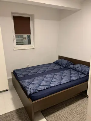 a bedroom with a bed with a blue comforter and a window at Apartman 