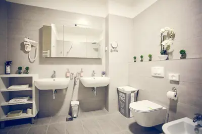a bathroom with two sinks and a toilet and a mirror at Apartmani SL Luxury in Banja Luka