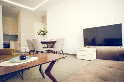 a living room with a table and a large screen tv at Apartmani SL Luxury in Banja Luka