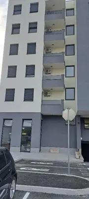 a tall building with a car parked in a parking lot at Zidart lux in Pištelići
