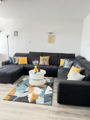 a living room with a black couch and a rug at Bajka centar in Bosanska Gradiška