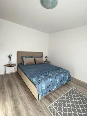 a bedroom with a bed with a blue comforter and a table at Bajka centar in Bosanska Gradiška