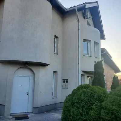 a white building with a white door and bushes at Vila Zvizdic- apartman in Ilijaš