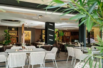 a restaurant with tables and chairs and plants at Edemus - Motel & Restaurant in Maglaj