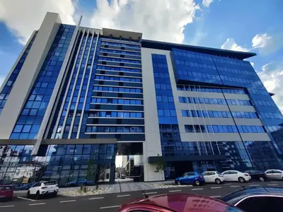 a tall building with cars parked in a parking lot at Yellow Submarine apartment Banja Luka in Banja Luka