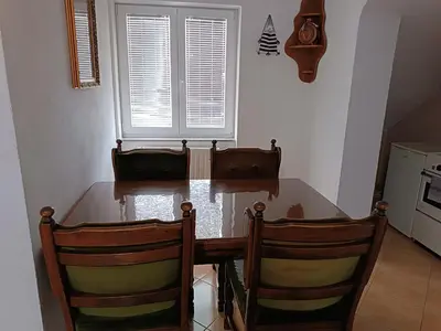 a kitchen with a wooden table and two chairs at Apartman Kaja in Kupres
