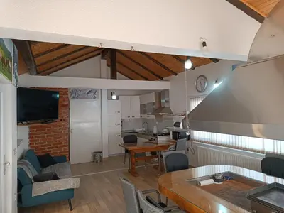 a living room with a table and a kitchen at Apartman Kaja in Kupres