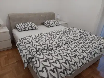 a bed with a black and white comforter and two pillows at Sunrise Apartments in Banja Luka