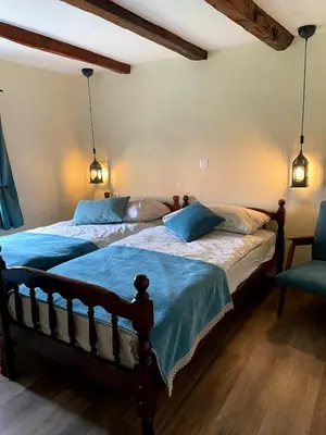 a bedroom with two beds with blue sheets and a chair at Begova kuća-Velika Kladuša in Velika Kladuša