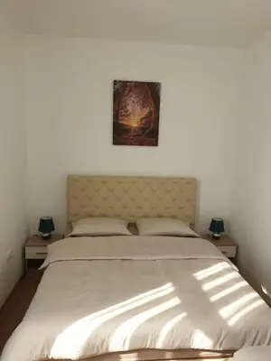 a bedroom with a large white bed with two lamps at Apartmani Marić in Gornji Vakuf