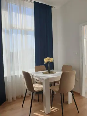 a white table with chairs and a vase of flowers on it at Apartmani Marić in Gornji Vakuf
