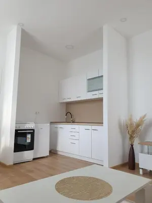 a white kitchen with white cabinets and a table at Apartmani Marić in Gornji Vakuf