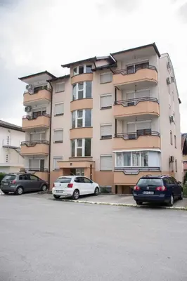 two cars parked in front of a large building at Apartman Vesna in Doboj