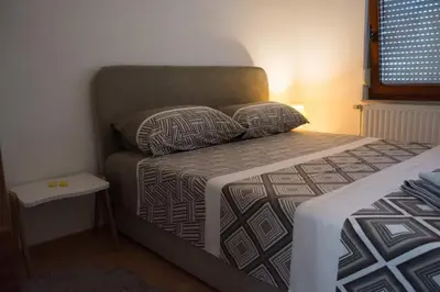a small bedroom with a bed and a side table at Apartman Vesna in Doboj