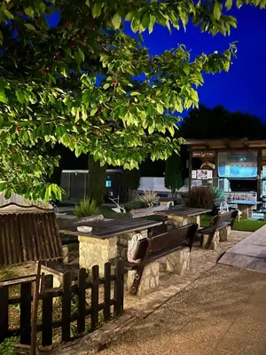 a row of park benches under a tree at night at Hotel Neron Bihać in Lohovo