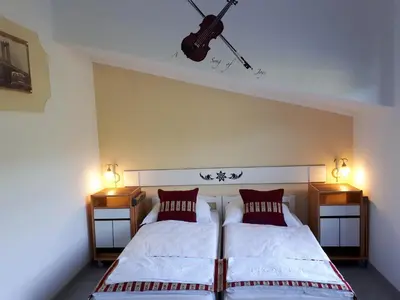 a bedroom with two beds and a guitar on the wall at Hotel Neron Bihać in Lohovo