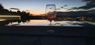 a glass of wine sitting on a table with the sunset at Villa Wineyard - VinoGrad in Banja Luka