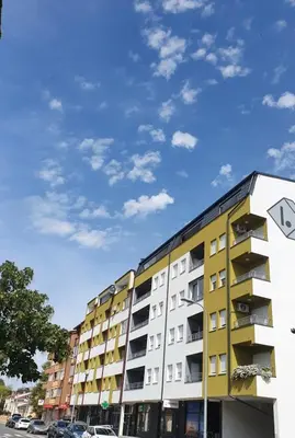 a yellow apartment building with a blue sky in the background at XENA Centar Gradiška in Bosanska Gradiška
