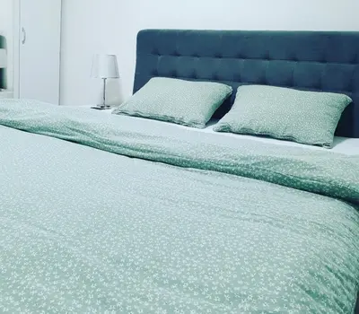 a large bed with a blue headboard and two pillows at XENA Centar Gradiška in Bosanska Gradiška