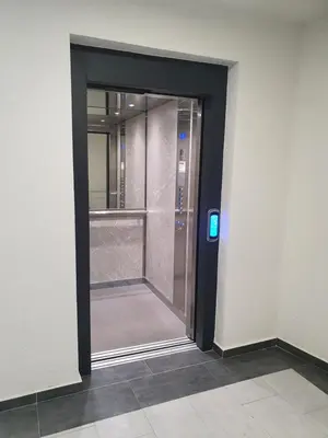 a glass elevator door in a building with a blue light at XENA Centar Gradiška in Bosanska Gradiška