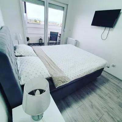a bedroom with a bed and a table and a window at XENA Centar Gradiška in Bosanska Gradiška
