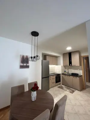 a kitchen with a dining room table with chairs and a kitchen with a refrigerator at Vert Apartment in Banja Luka