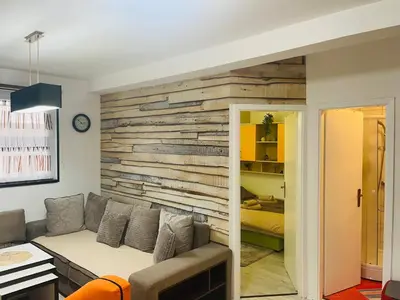 a living room with a wooden accent wall at Apartman SkiBeg, Vlašić in Vlasic