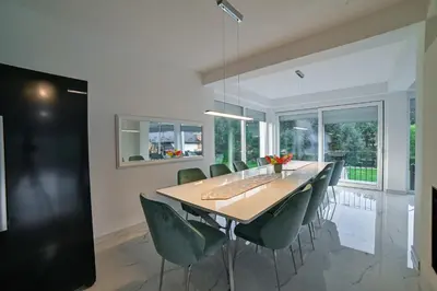 a dining room with a wooden table and green chairs at Summer Residence Una in Bihać