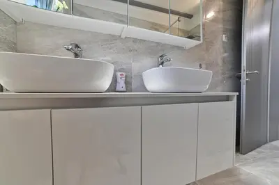 two sinks in a bathroom with white cabinets at Summer Residence Una in Bihać