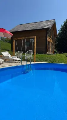 a swimming pool with two chairs and a house at Vikendica Brvnara Marčetić in Banja Luka