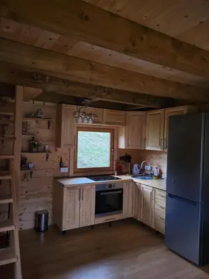 a kitchen with wooden cabinets and a refrigerator and a window at Vikendica Brvnara Marčetić in Banja Luka