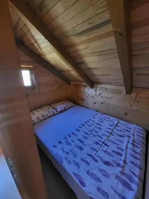 a bed in a wooden room with a wooden ceiling at Vikendica Brvnara Marčetić in Banja Luka