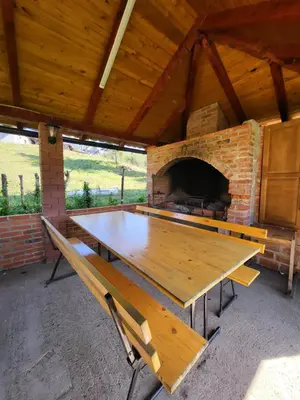 a wooden table and benches in a pavilion with a fireplace at Vikendica Brvnara Marčetić in Banja Luka