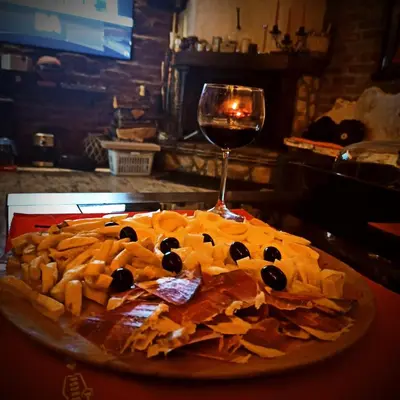 a pizza with cheese and olives and a glass of wine at Villa FORESTA in Banja Luka